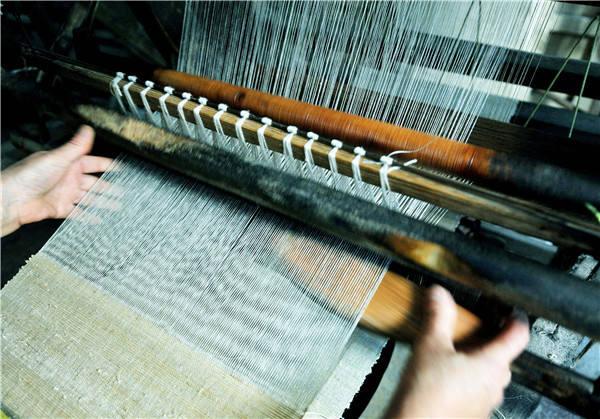 7月17日,信州区沙溪镇沙溪村农民正在用传统织布机手工纺织夏布.